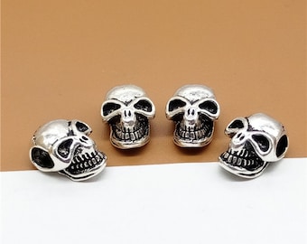 Puede incluir: Cuatro cuentas de calavera de plata con detalles faciales. Las calaveras tienen un acabado ligeramente desgastado.
