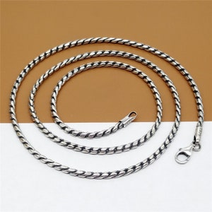 May include: A silver chain necklace with a twisted rope design. The chain is approximately 20 inches long and has a lobster clasp closure.