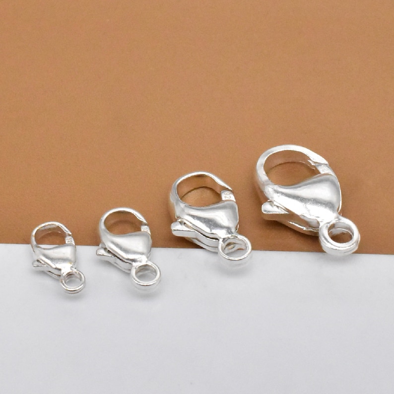 K&ouml;nnte beinhalten: Vier silberne Karabinerverschl&uuml;sse in verschiedenen Gr&ouml;&szlig;en. Die Verschl&uuml;sse sind ein beliebtes Schmuckzubeh&ouml;r f&uuml;r Halsketten, Armb&auml;nder und andere Schmuckprojekte.