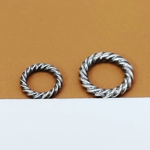 Può includere: Due anelli di salto in argento con un design a corda intrecciata. L'anello più grande ha un diametro di circa 2,5 cm e l'anello più piccolo ha un diametro di circa 1,25 cm.