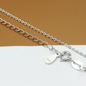 Op de afbeelding: Een zilveren ketting met een karabijn sluiting en een klein label met de tekst "925".