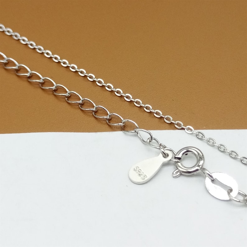 Op de afbeelding: Een zilveren ketting met een karabijn sluiting en een klein label met de tekst "925".
