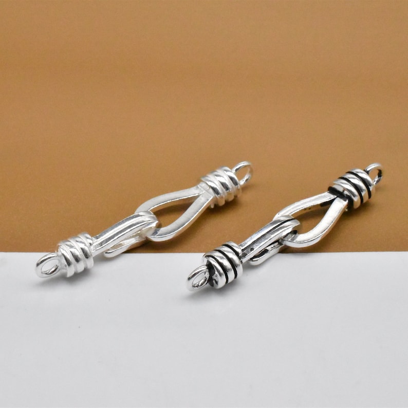May include: Two silver-toned metal clasps with a twisted rope design. The clasps are designed to be used as a connector for jewelry.