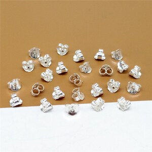 May include: A collection of 20 silver earring backs. The backs are designed to secure earrings to the earlobe.