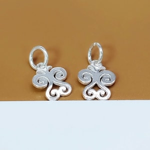 May include: Two silver charm pendants with a swirl design. Each pendant has a loop at the top for attaching to a chain or bracelet.