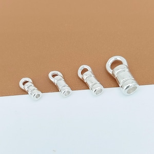 May include: Four silver-toned metal crimp end caps arranged in a row from smallest to largest. Each piece features a cylindrical body with a smooth finish and a small circular loop at the top for attachment, designed for jewelry making projects.