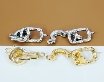 May include: Four silver and gold metal clasps for jewellery making. The clasps are in the shape of a square with a rounded edge and a small loop on one side. The clasps are designed to be used for necklaces, bracelets, and other jewellery.
