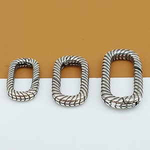 May include: Three silver-toned metal rings with a textured, braided design. The rings are different sizes and are arranged in a row from smallest to largest.