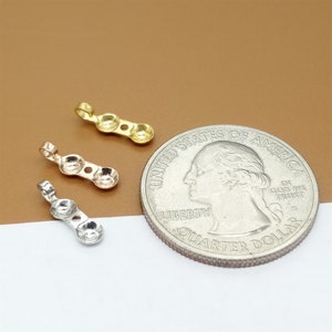 May include: Three pendant charms in gold, rose gold, and silver. Each charm has three round beads and a loop at the top. The charms are shown next to a US quarter for size comparison.