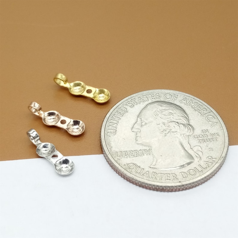 May include: Three pendant charms in gold, rose gold, and silver. Each charm has three round beads and a loop at the top. The charms are shown next to a US quarter for size comparison.