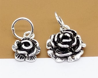 May include: Two silver rose charms, one with a loop for attaching to a chain or bracelet, the other with a jump ring. Both charms feature a detailed rose design.