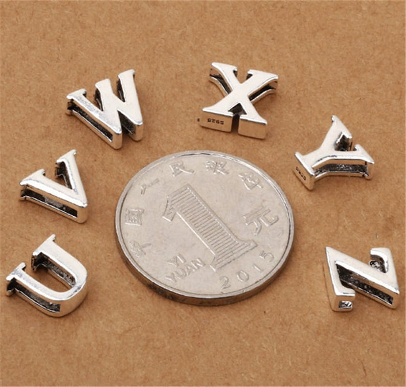May include: Silver charm letters in the alphabet, including the letters U, V, W, X, Y, and Z. The charms are small and delicate, perfect for adding a personalized touch to jewelry.