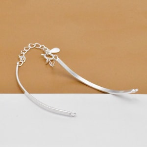 May include: A silver bracelet with a curved design and a lobster clasp closure.