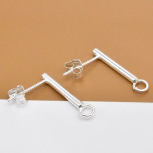 May include: A pair of silver earring posts with a small loop at the end of each post.