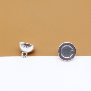 May include: Two silver magnetic clasps for jewelry making. One clasp is a round disc with a flat surface. The other clasp is a dome shape with a loop on the bottom. Both clasps have the number "S265" engraved on them.