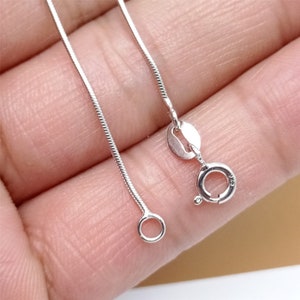 May include: A silver snake chain necklace with a lobster clasp closure.