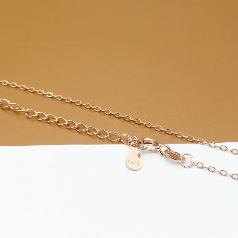 Op de afbeelding: Een ketting van ros&eacute;goud met een karabijn sluiting en een klein label met het nummer "5825" erop.