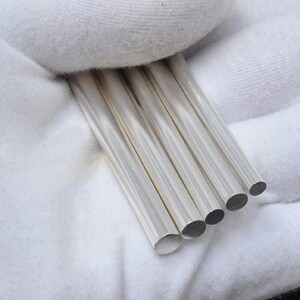 May include: Five silver metal rods of varying lengths, arranged in a row, with the ends of the rods visible.