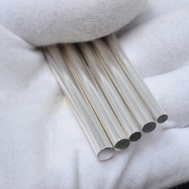 May include: Five silver metal rods of varying lengths, arranged in a row, with the ends of the rods visible.