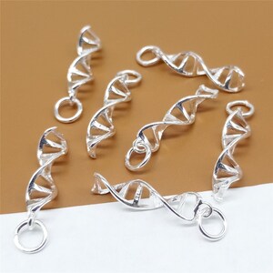 K&ouml;nnte beinhalten: Ein Satz silberfarbener DNA-Doppelhelix-Anh&auml;nger. Die Anh&auml;nger sind aus Metall und haben eine gl&auml;nzende Oberfl&auml;che. Sie sind perfekt, um Ihren Schmuck mit einem Hauch von Wissenschaft zu versehen.