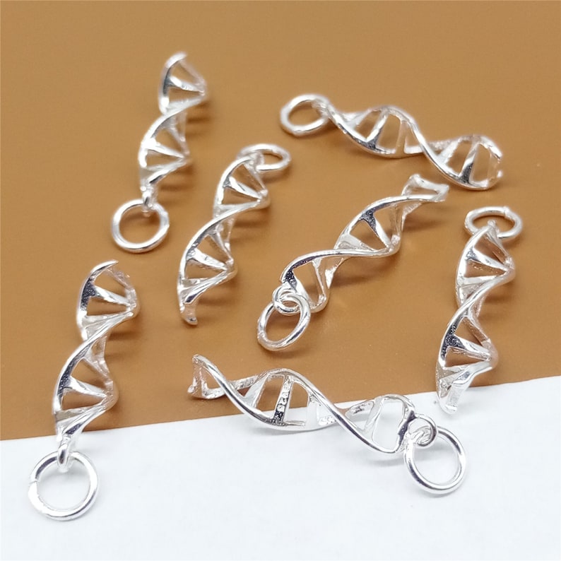 K&ouml;nnte beinhalten: Ein Satz silberfarbener DNA-Doppelhelix-Anh&auml;nger. Die Anh&auml;nger sind aus Metall und haben eine gl&auml;nzende Oberfl&auml;che. Sie sind perfekt, um Ihren Schmuck mit einem Hauch von Wissenschaft zu versehen.