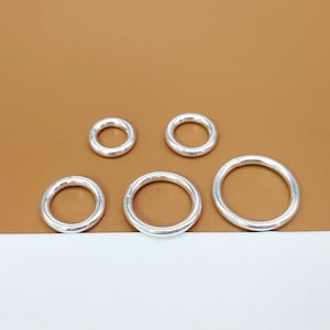 Op de afbeelding: Vijf zilveren springringen in verschillende maten. De ringen zijn glad en glanzend.