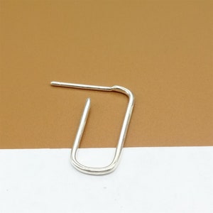 May include: A silver hoop earring with a simple oval shape.