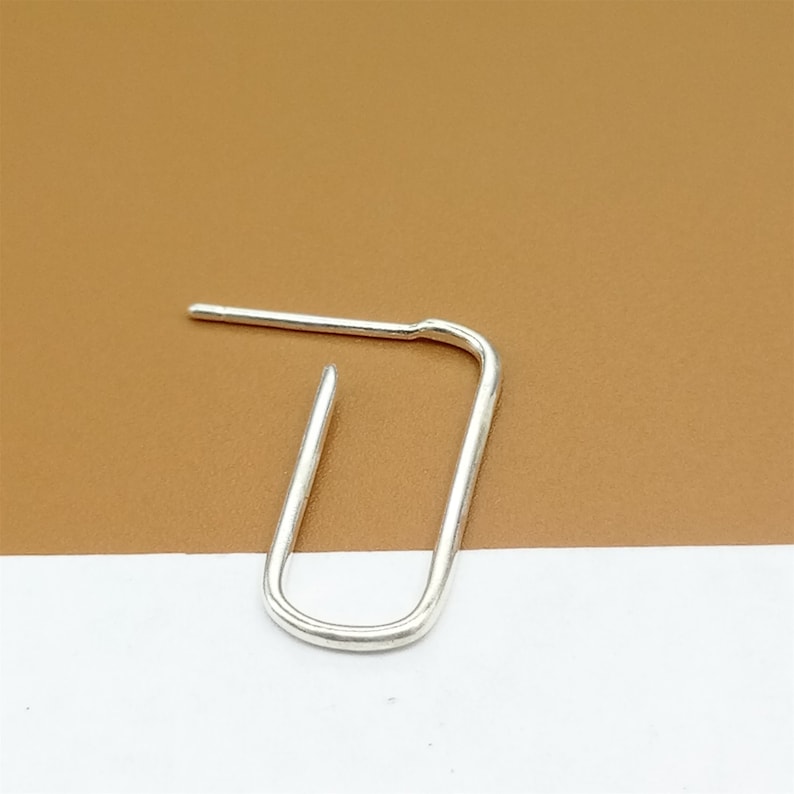 May include: A silver hoop earring with a simple oval shape.