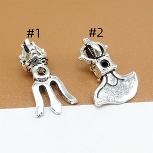 May include: Two silver charms, one shaped like a trident and the other like an axe, with the numbers #1 and #2 printed above them.