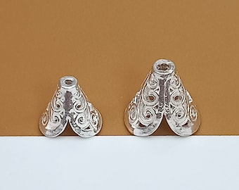 May include: Two silver metal cone-shaped decorative end caps with an intricate, swirling design. The larger end cap is about 2 inches in diameter and the smaller end cap is about 1.5 inches in diameter.