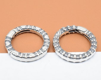 May include: Two silver rings with intricate designs. One ring has a pattern of hearts and the other has a pattern of dots.