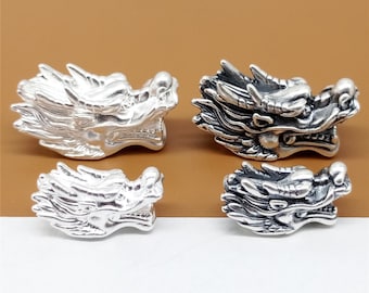 May include: Four silver dragon head charms. The dragon heads are detailed and have a textured finish. The charms are perfect for adding a touch of whimsy to jewelry or other crafts.