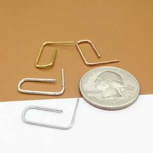 May include: Four small hoop earrings, two gold and two silver, are arranged on a white surface next to a US quarter. The earrings are all about the size of the quarter.