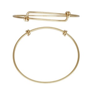 May include: A gold-toned expandable bangle bracelet with a simple design. The bracelet is made of metal and has a smooth finish.