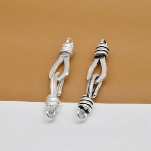 May include: Two silver-toned metal clasps with a twisted rope design. The clasps have a loop on each end.