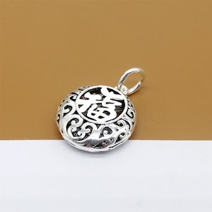 May include: Silver pendant with a circular design featuring the Chinese character for "fortune" in a decorative, openwork style.