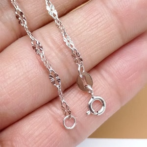 May include: A silver chain necklace with a delicate, patterned design. The chain has a lobster clasp closure.