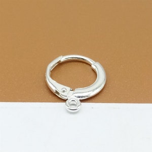 May include: Silver hoop earring with a small jump ring attached to the bottom.