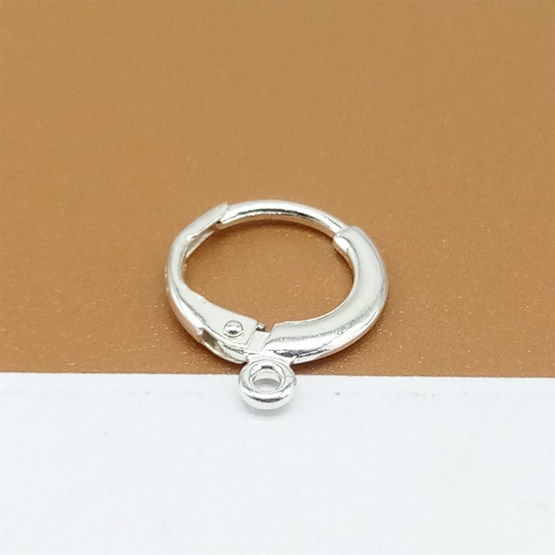 May include: Silver hoop earring with a small jump ring attached to the bottom.