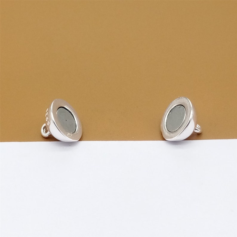 May include: Two silver magnetic clasps for jewelry making. Each clasp has a round, flat, silver-toned surface with a small loop on the side.