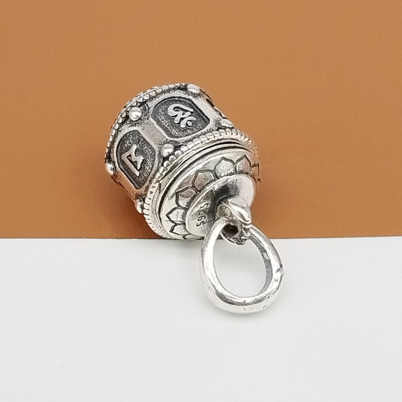Puede incluir: Encanto de plata con un dise&ntilde;o de molinillo de oraci&oacute;n giratorio. El encanto tiene un bucle para sujetarlo a un collar o pulsera. El molinillo de oraci&oacute;n est&aacute; grabado con caracteres tibetanos.