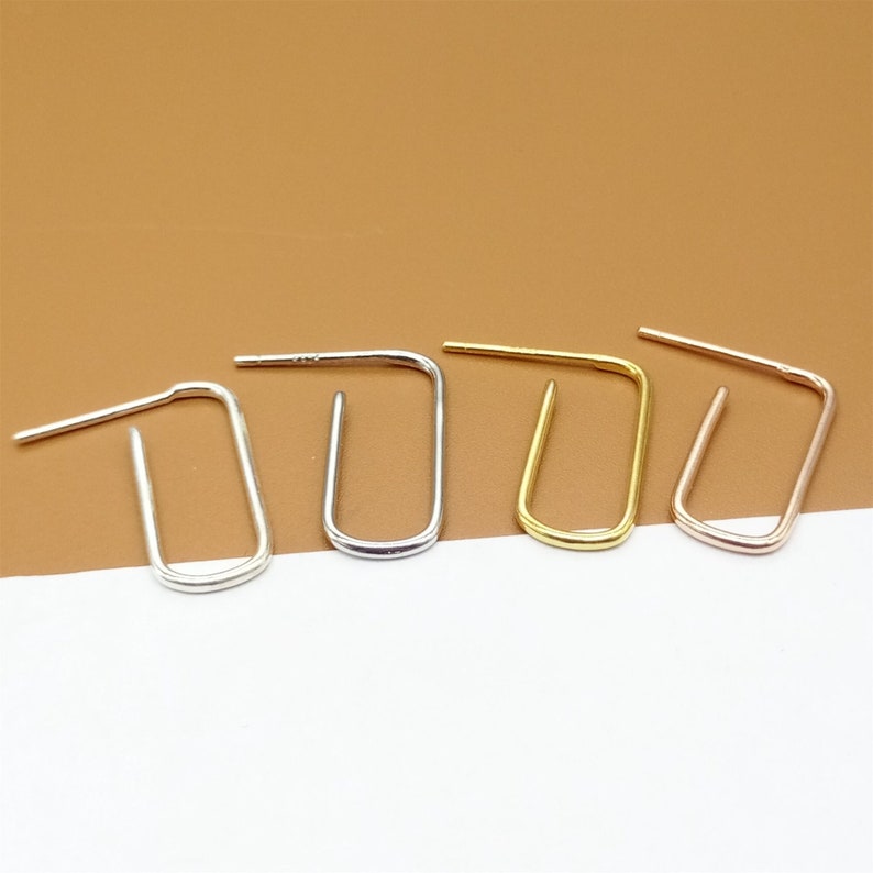 May include: Four minimalist hoop earrings in silver, gold, and rose gold. The earrings are simple and elegant, and would make a great addition to any jewelry collection.