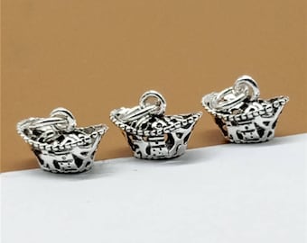 May include: Three silver charm pendants in the shape of a traditional Chinese gold ingot. Each pendant has intricate details and a loop for attaching to a bracelet or necklace.