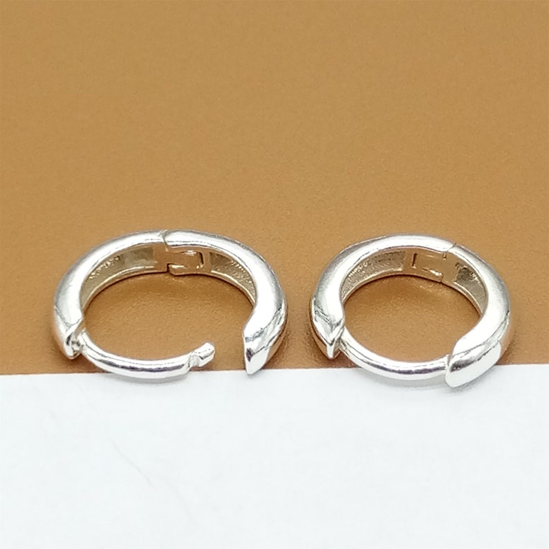 May include: A pair of silver hoop earrings. The earrings are simple and classic, with a smooth finish.