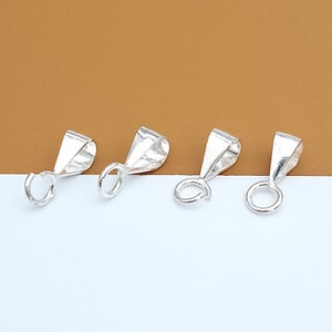 May include: Four silver-toned pendant bails with a loop at the bottom. The bails are designed to attach to a chain or cord.