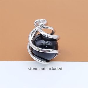 Peut inclure: Un pendentif argenté avec un design en spirale retenant une pierre noire et sphérique. Le pendentif a une boucle en haut pour une chaîne. Le texte "stone not included" est en bas.