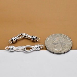 May include: Two silver-toned metal clasps for jewelry making. The clasps are about the size of a US quarter.