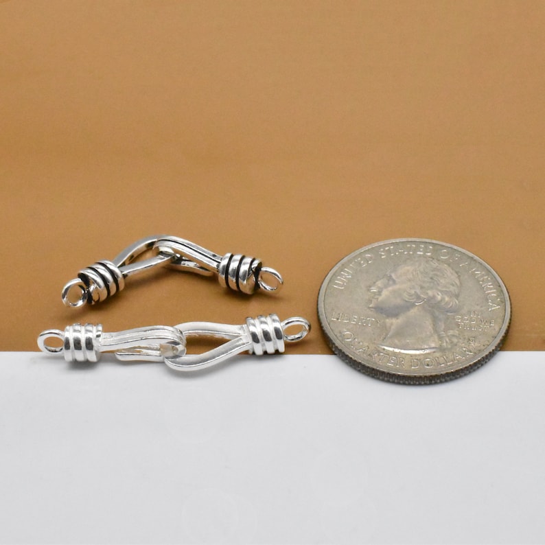 May include: Two silver-toned metal clasps for jewelry making. The clasps are about the size of a US quarter.