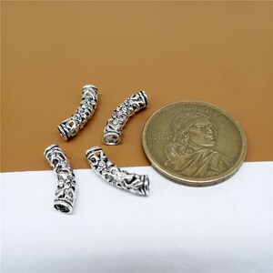 May include: Four silver-toned metal bead caps with a floral design. The bead caps are curved and have a hollow center.
