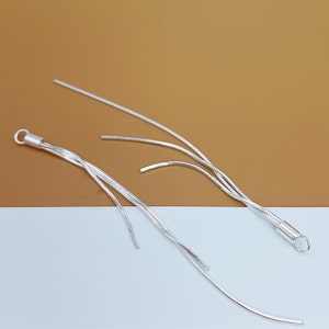 May include: A pair of silver dangle earrings with multiple strands of chain hanging from a small silver loop.